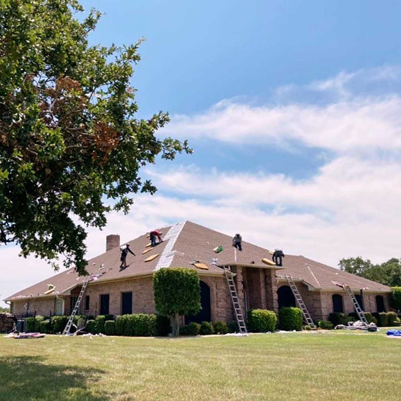 A ranch home with ladders against the eaves during a reroof