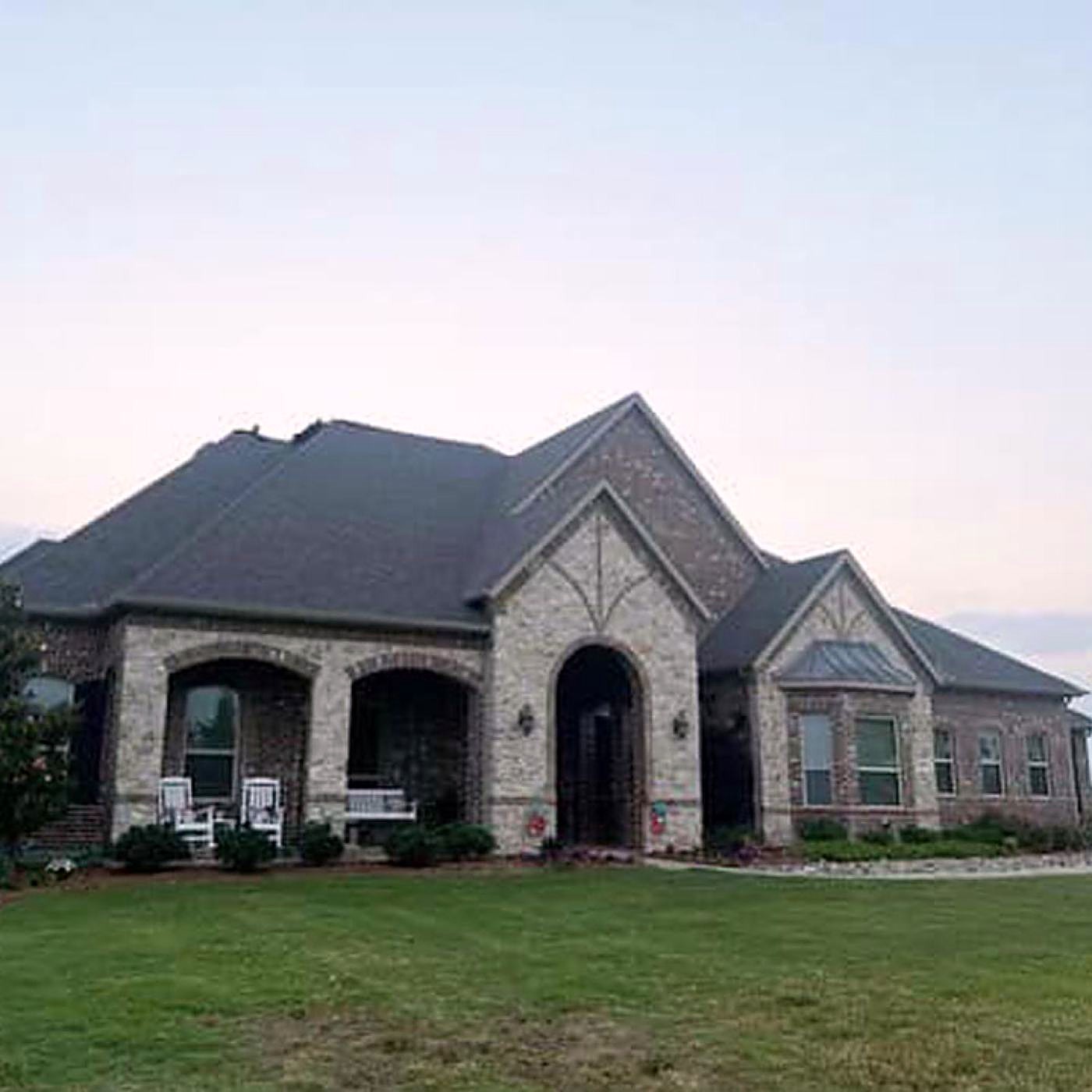 The front elevation of a stone-fronted house with a finished architectural shingle roof